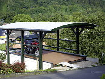 Attraktive Konstruktion eines Rundbogendachs mit grünen Holzbalken als Schutz für ein Motorrad