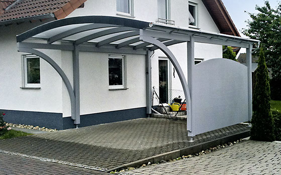 Modernes Rundbogendach mit grauen Holzbalken als Carport